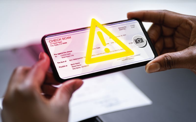 Mobile deposit scam alert triangle over phone